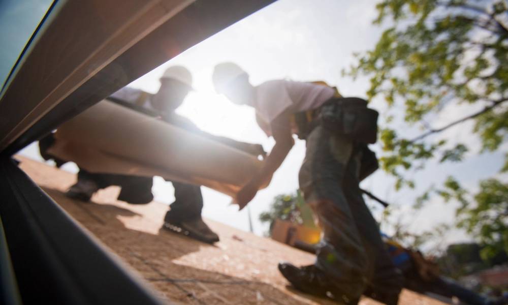 Two construction workers working on a roof.