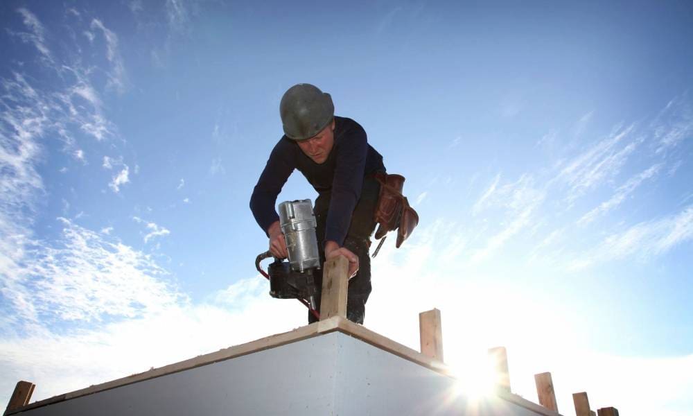 A construction worker is working on a roof.