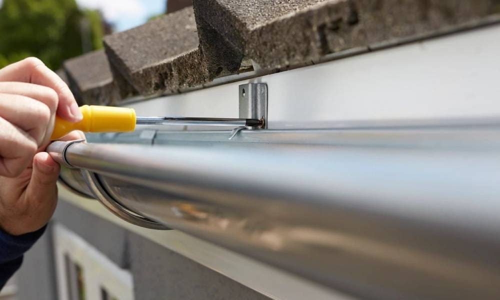 A person fixing a gutter on a house.