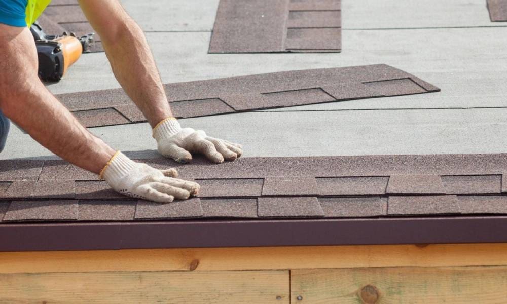 A man is installing shingles on a roof.