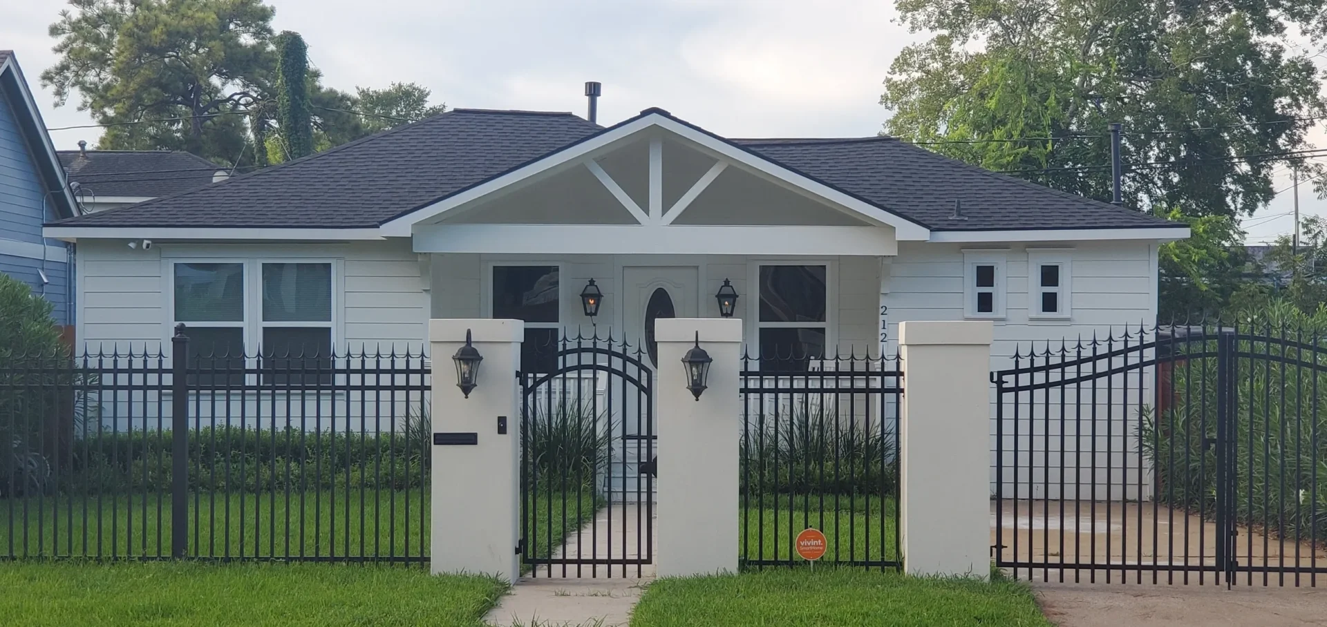 A white house with a black fence in front of it.