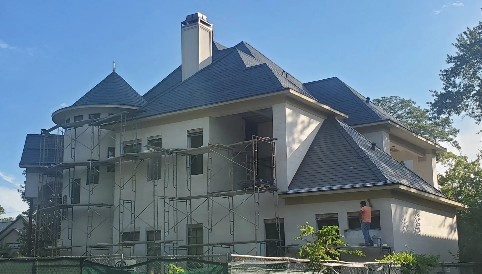 Large house with scaffolding and a worker.